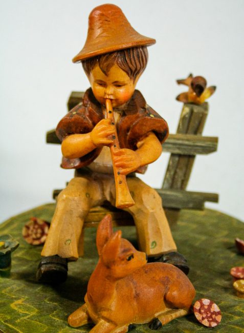 Particolare di carillon vintage scolpito in legno e dipinto a mano Anri, bambino che suona il flauto